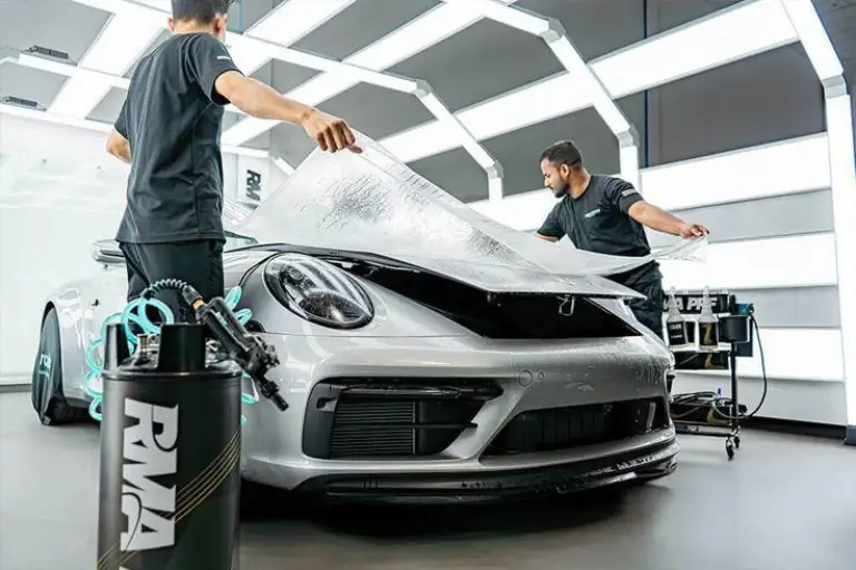 Professional automotive detailer following a structured paint correction process in a modern detailing studio