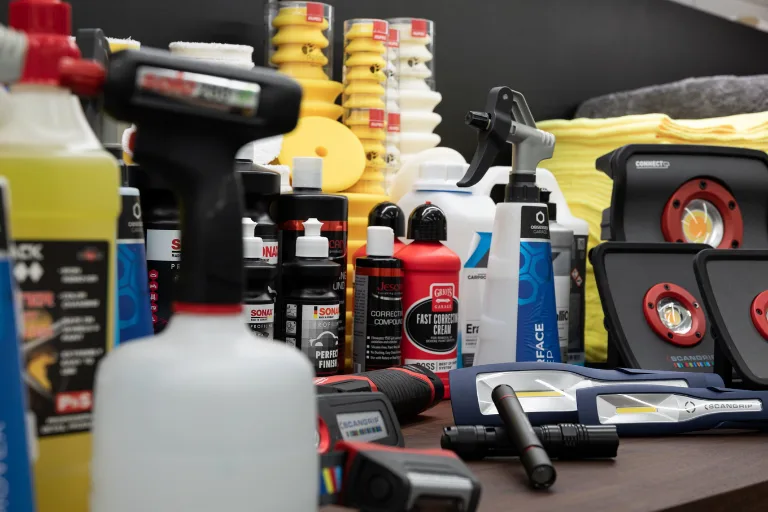 Professional automotive detailing business with technicians working on luxury vehicles in a modern detailing studio