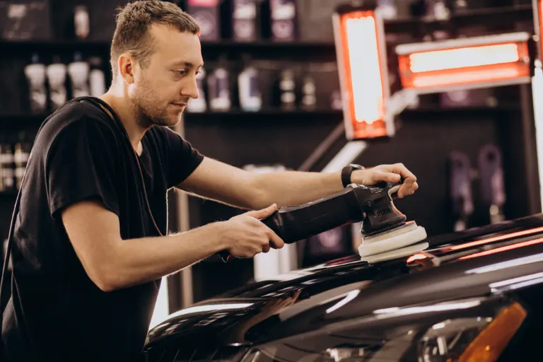 Modern automotive detailing business with professional technicians working on a luxury vehicle in a premium detailing studio