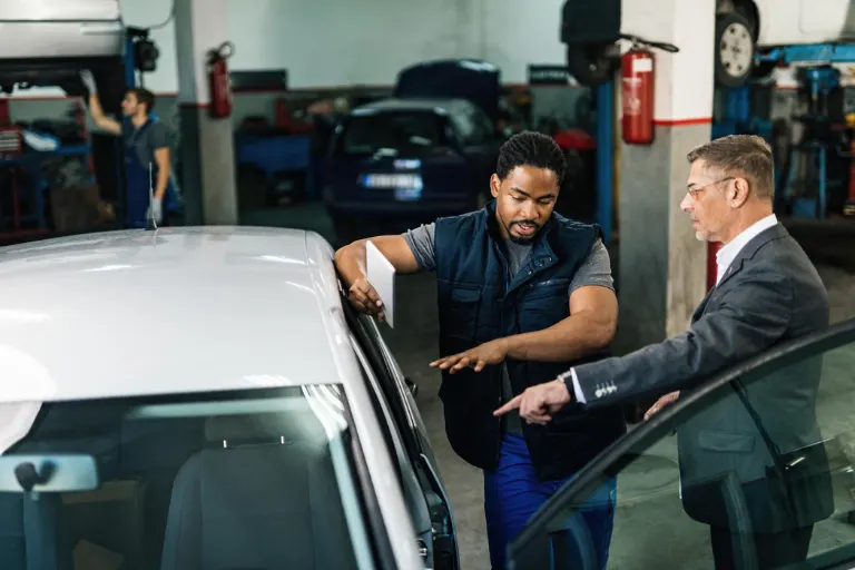 Professional detailing business owner managing a luxury vehicle detailing studio with trained technicians and modern equipment