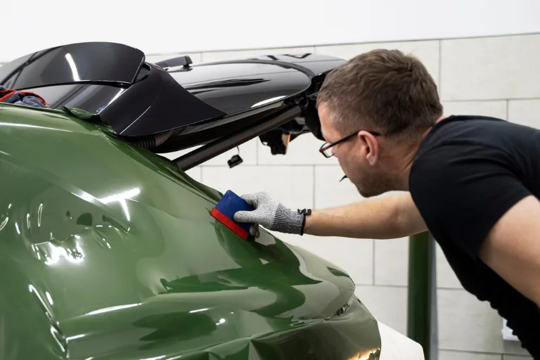 Professional detailer comparing paint protection film options before installing PPF on a luxury vehicle