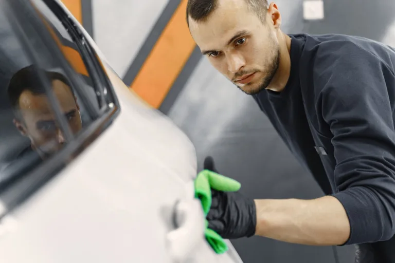 Professional detailer inspecting paint defects on a vehicle before starting a paint correction job
