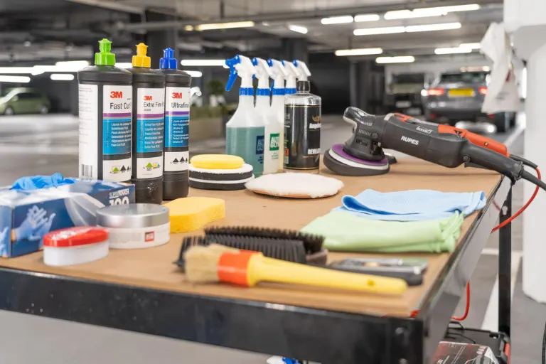 Automotive detailing products displayed in a professional distribution warehouse with logistics and customer support team