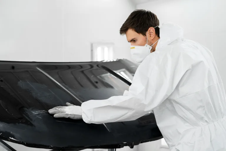 Professional detailer performing a paint correction test spot on a car bonnet under an inspection light.